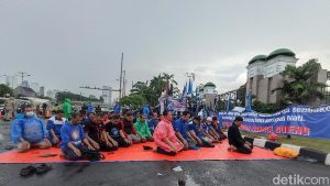 Buruh Demo di DPR Gelar Salat Zuhur Berjemaah di Tengah Guyuran Hujan.